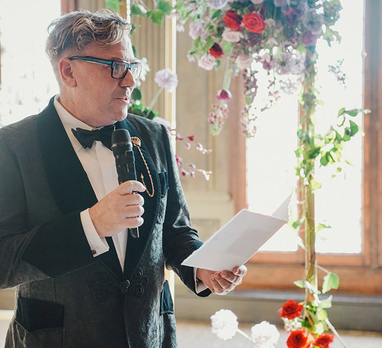 Groom in black tuxedo reading wedding vows 