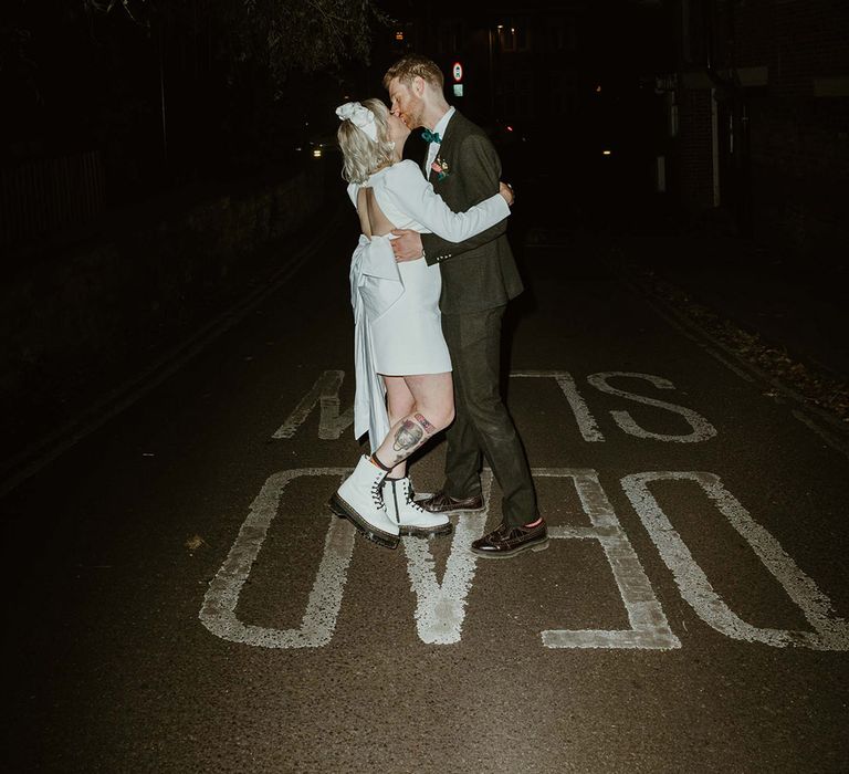 Bride wearing short wedding dress with white Doc Marten wedding shoes kissing groom 