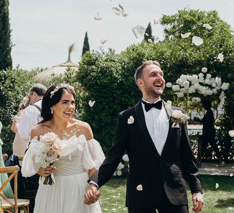 White rose petal confetti moment for the bride and groom as they walk back down the aisle at the outdoor wedding as a married couple