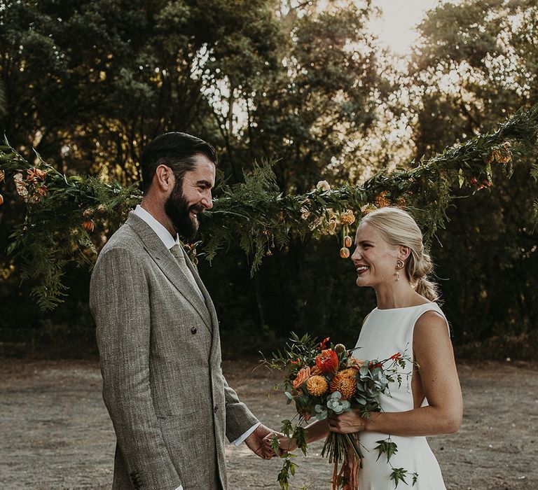 Bride and groom holding hands at outdoor wedding ceremony 