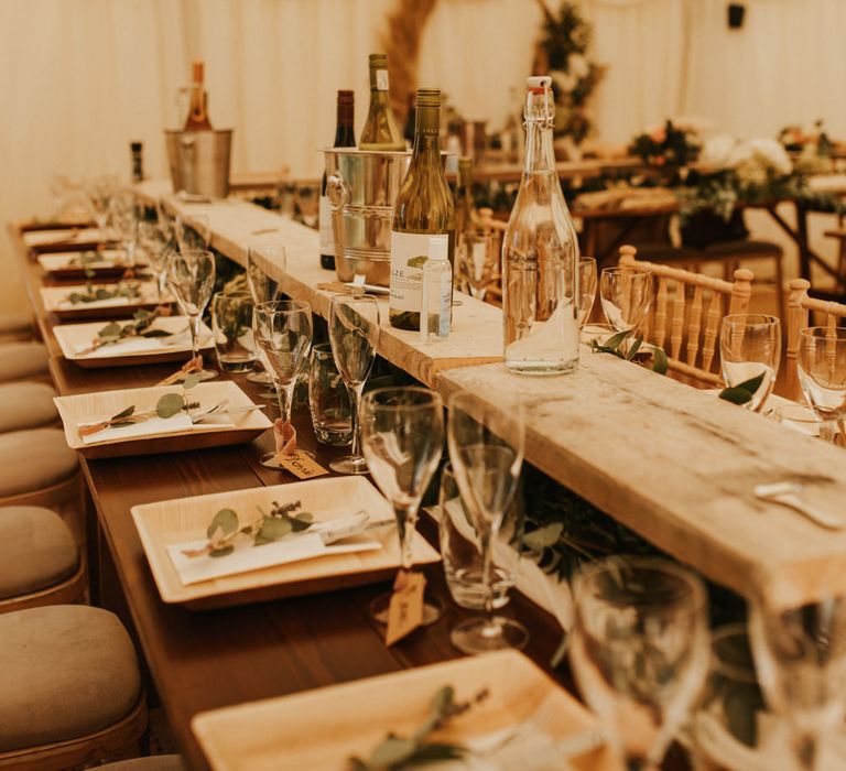 Top table with bamboo plates, foliage decor and luggage tag name place cards