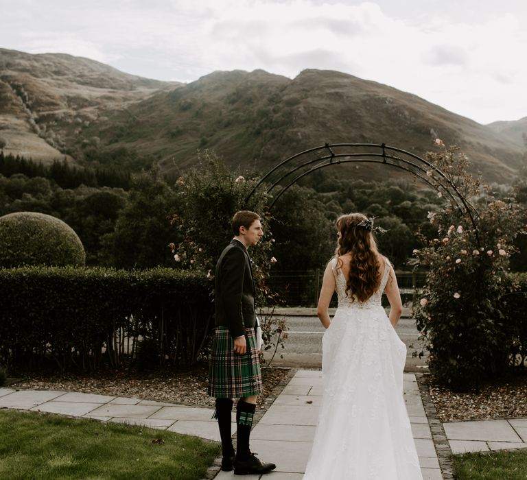 Bride wearing low back floral sparkly wedding dress with groom in traditional Scottish kilt