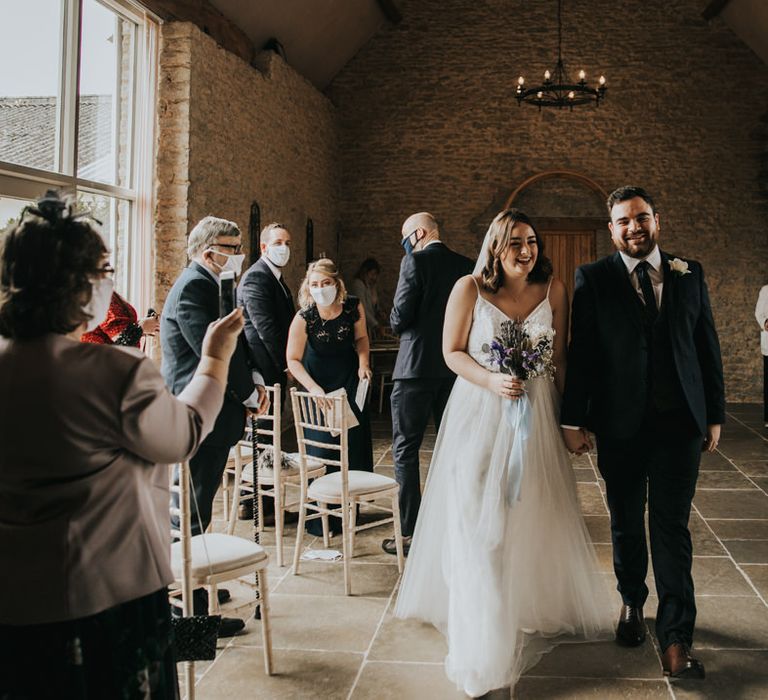 Smiling bride and groom walking down the aisle