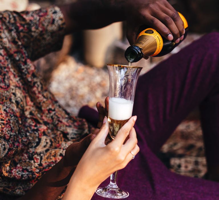 Groom pours champagne in outdoor dining