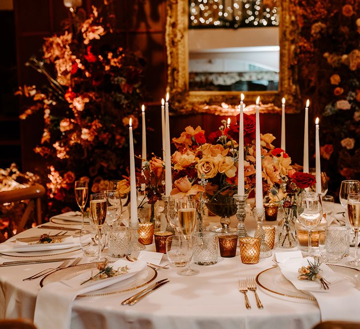 Winter wedding tablescape with large centrepiece of warm neutral tones and tapered candles.