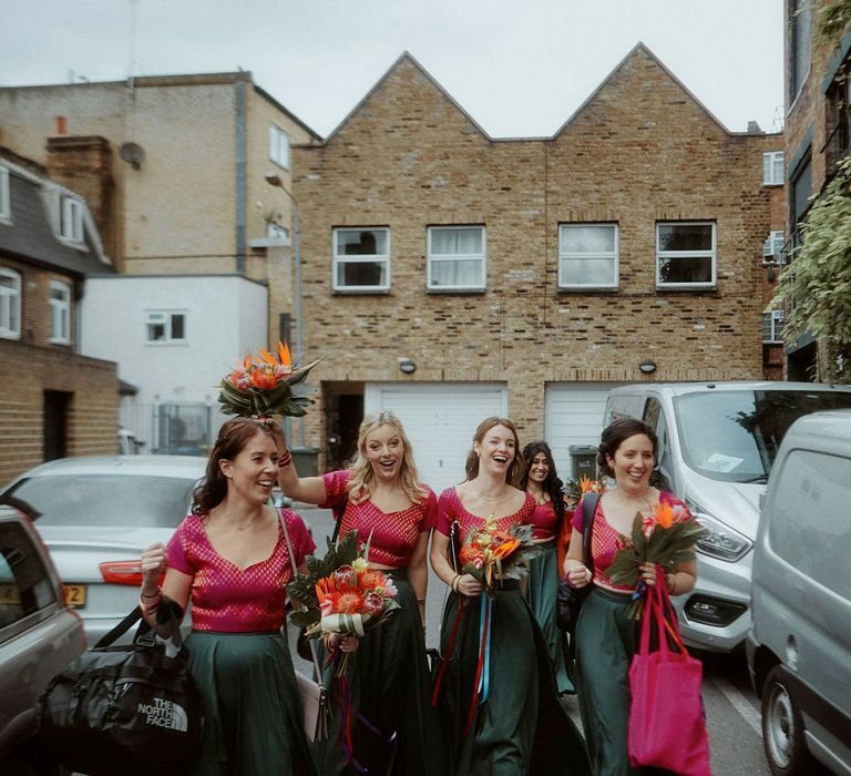 Bridesmaids in pink and green lenghas walking through the street 