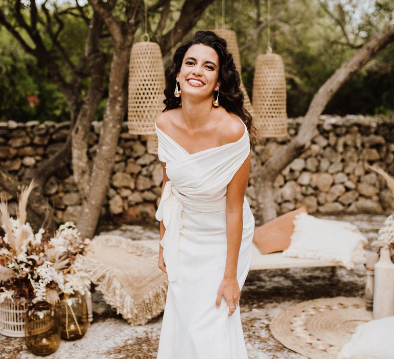 Bride laughs outdoors with wicker lampshades in Mallorca countryside