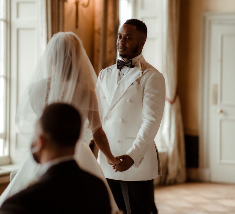 Groom in a white double breasted jacket with black bow tie 