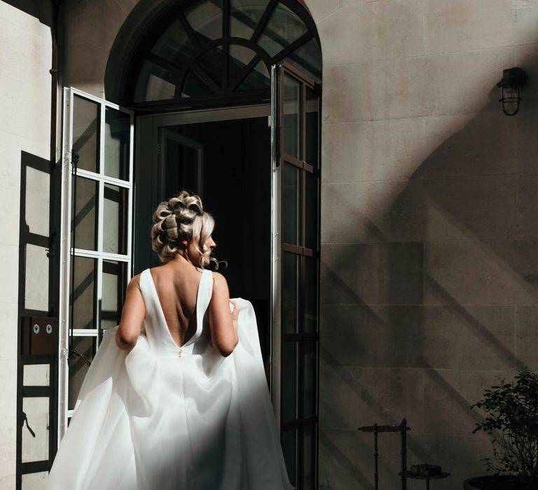 Bride wears her hair in curlers as she walks through the door