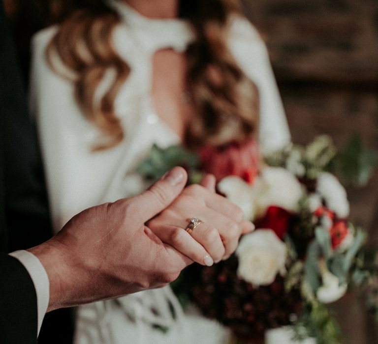 The groom holding the brides hand, her wedding ring prominently displayed