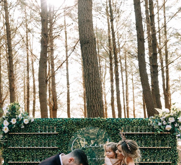 Bride and groom with their kids in front of Prosecco wall