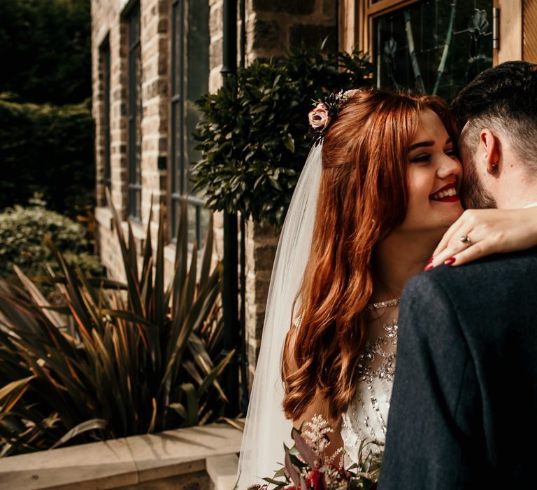 Bride & groom kiss on wedding day whilst outdoors in the sunshine