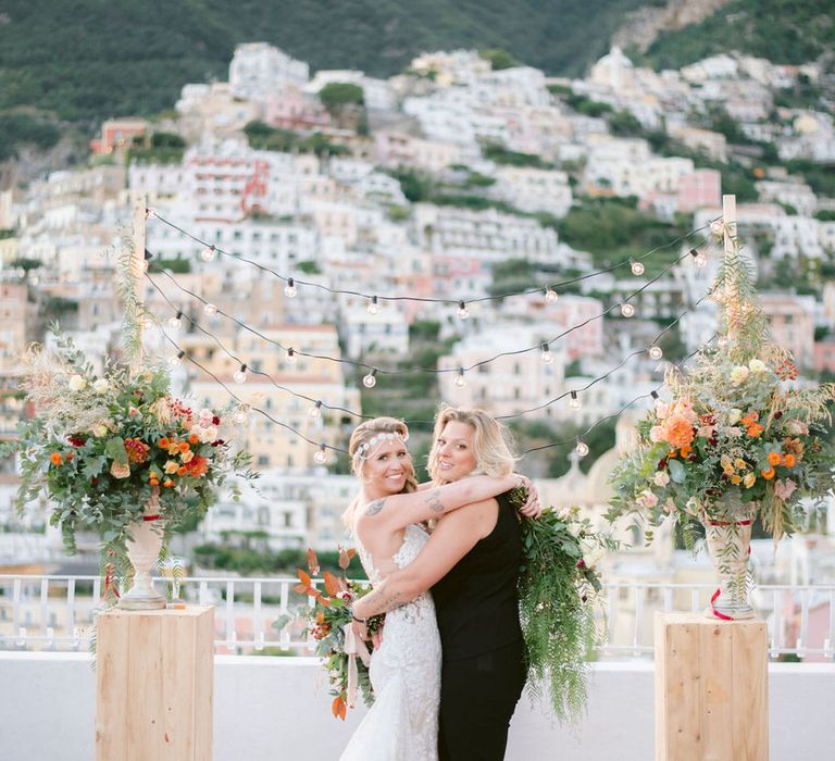 The beautiful brides hugging at the altar between two floral centrepieces