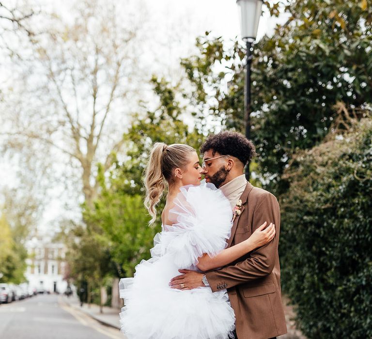 Portrait of a groom in a brown check blazer and bride in a short layered tulle wedding dress 