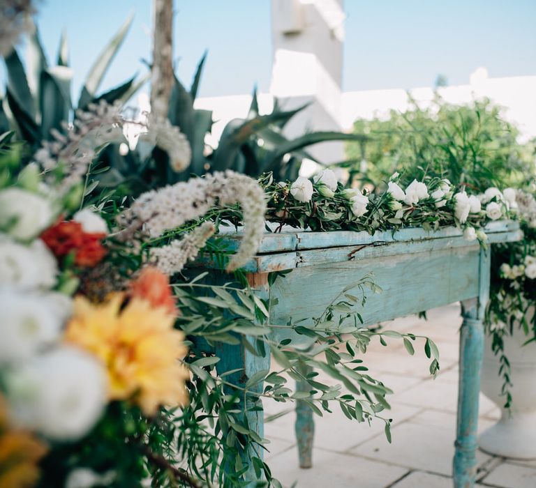 Orange and white flower centrepieces with olive leaf foliage and garlands with wildflowers