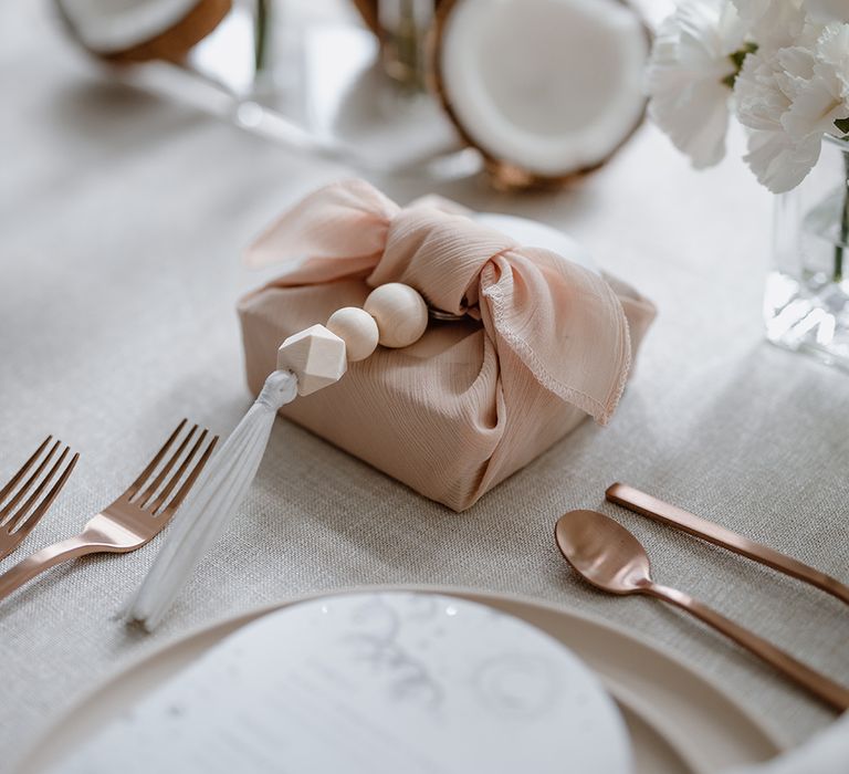 Wedding favour wrapped in a blush fabric with wooden bead detail