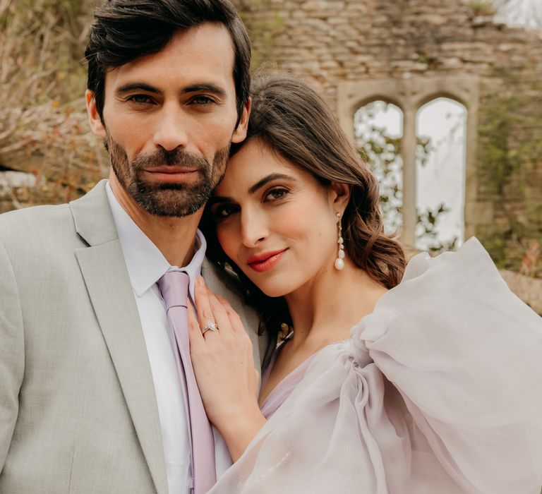 Bride leans into groom as he wears pale suit 