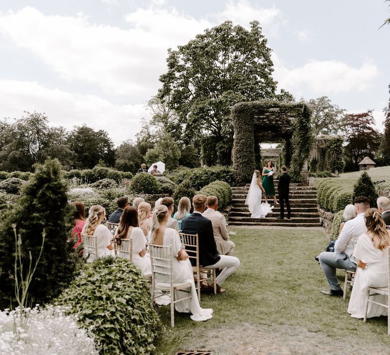 Wedding guests seated aside the aisle outdoors