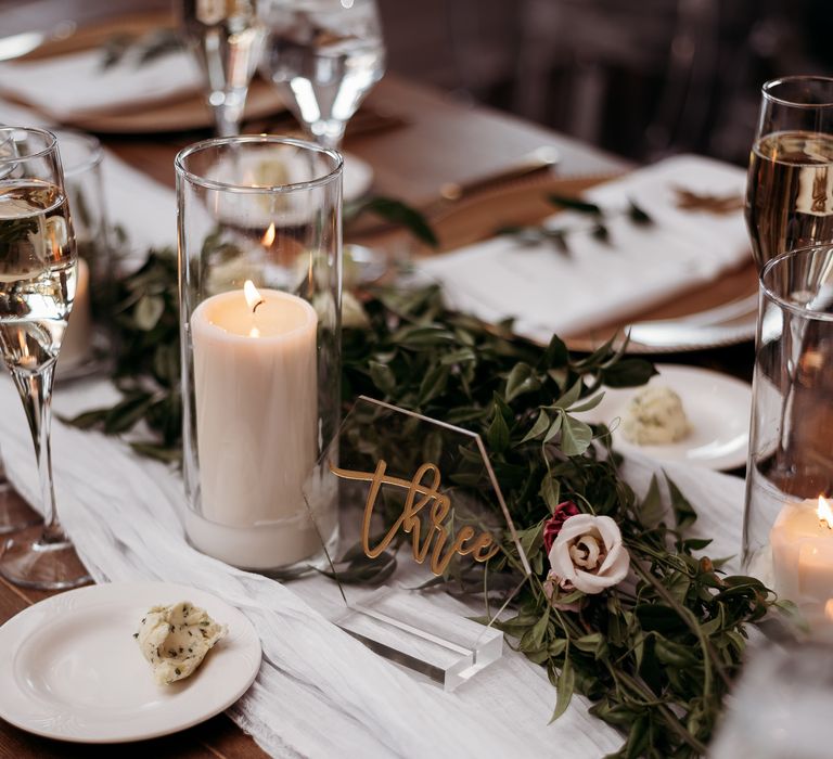 Tablescape with green table runner and white pillar candles