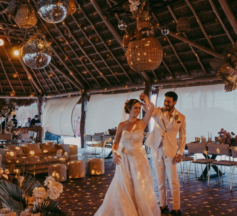 Groom spins bride around on her wedding day as they dance underneath disco balls 