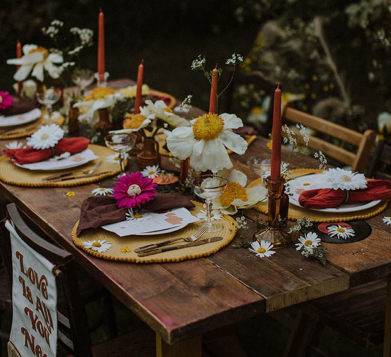 wooden table with red, orange, yellow, brown and gold table decor and flowers 