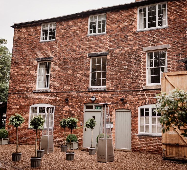 Exterior of The West Mill Derby with red brick, pale green windows and doors and gravelled front 