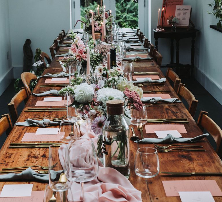 Pink table runner across wooden table complete with pink and white florals