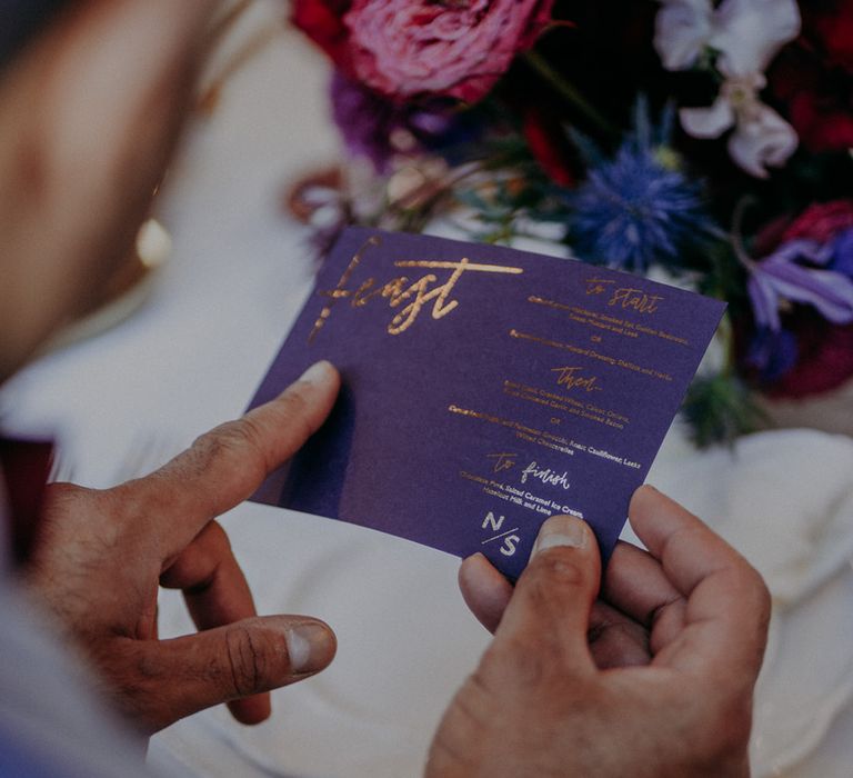 Purple menu card with gold foil font and braille 