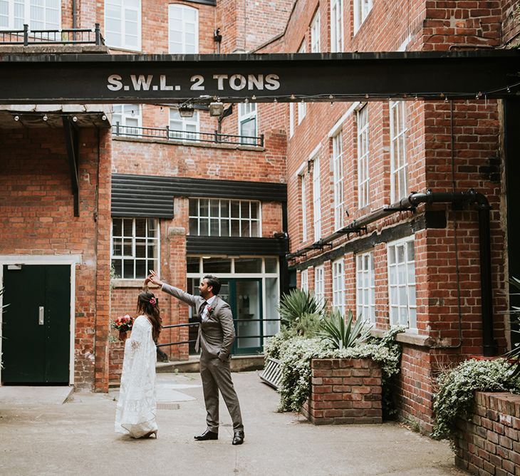 An Indian British bride and groom dance outside their industrial wedding venue.