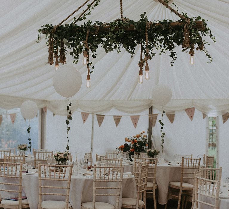 Marquee wedding reception decor with bunting, balloons and rustic handing installation wrapped in rope, festoon lights and ivy