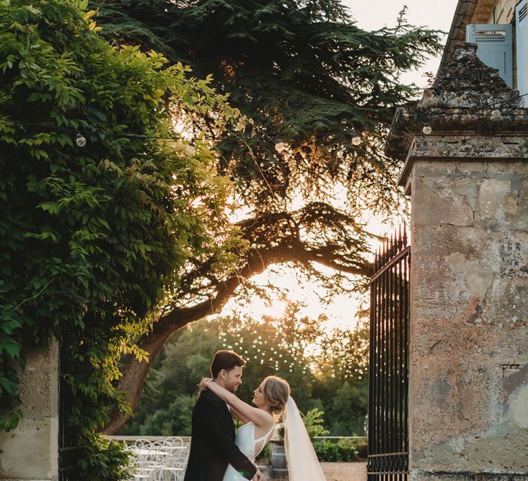 Bride and groom portrait in front of the gates at Chateau Lagorce with groom in a tuxedo and bride a Stella York wedding dress