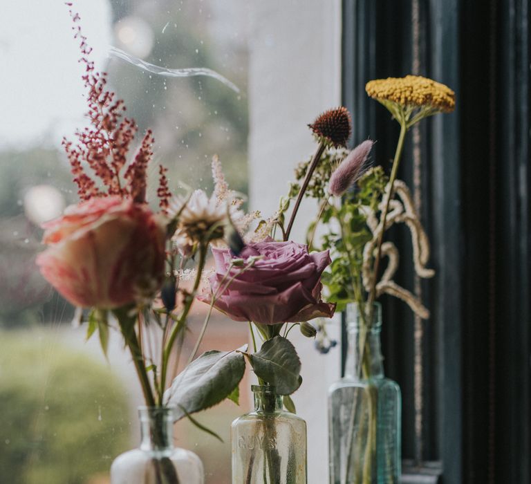 Glass bottles with pastel flower stems in 