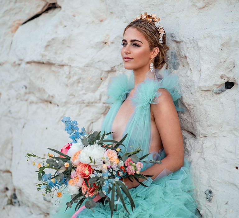 Bride in a mint green wedding dress holding a pastel flower bouquet by the rocks at her Botany Bay elopement 