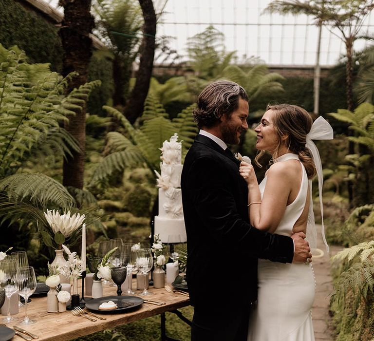 Black tie wedding with bride and groom dancing next to their intimate tablescape 