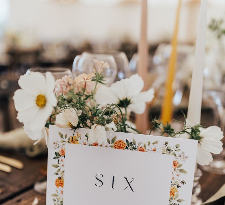 Table place name with floral illustration and white florals on rustic wooden table for wedding reception