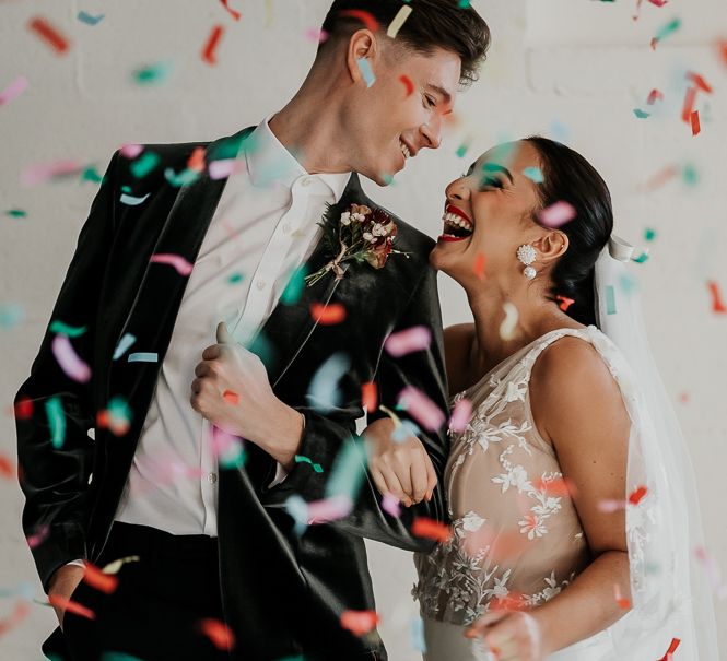 Bride & groom look lovingly at one another as confetti is thrown around them