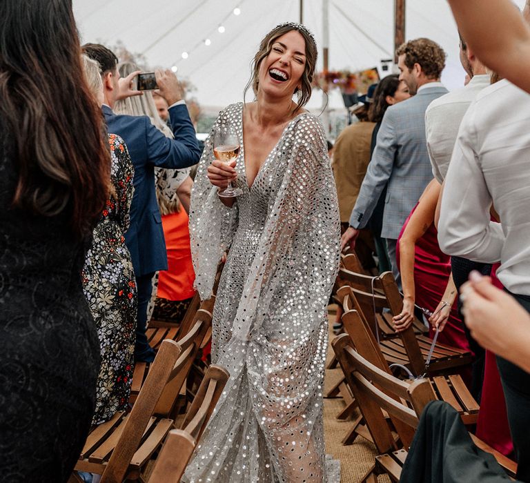 Bride in a silver sequin wedding dress walking through her marquee wedding reception