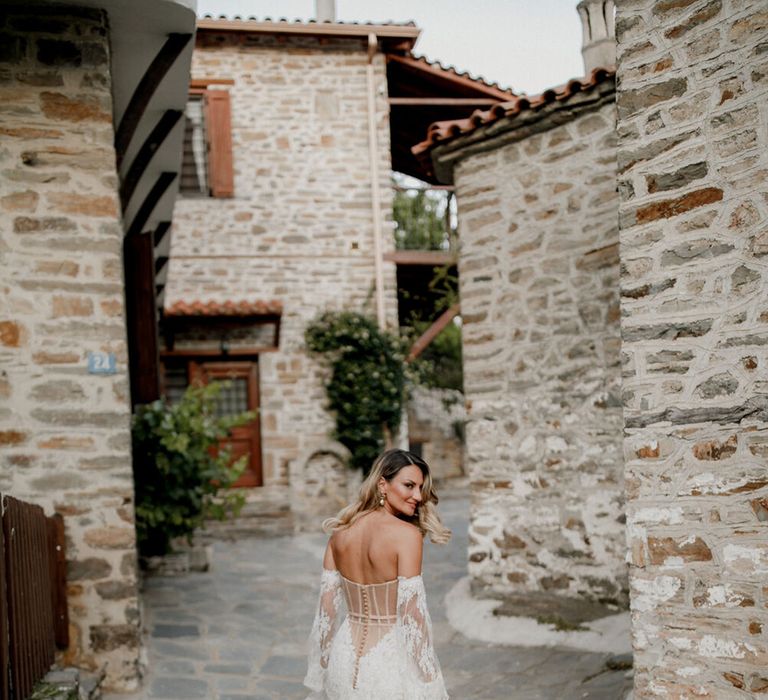 Bride wears lace wedding gown complete with buttons to the back and V-shaped styling