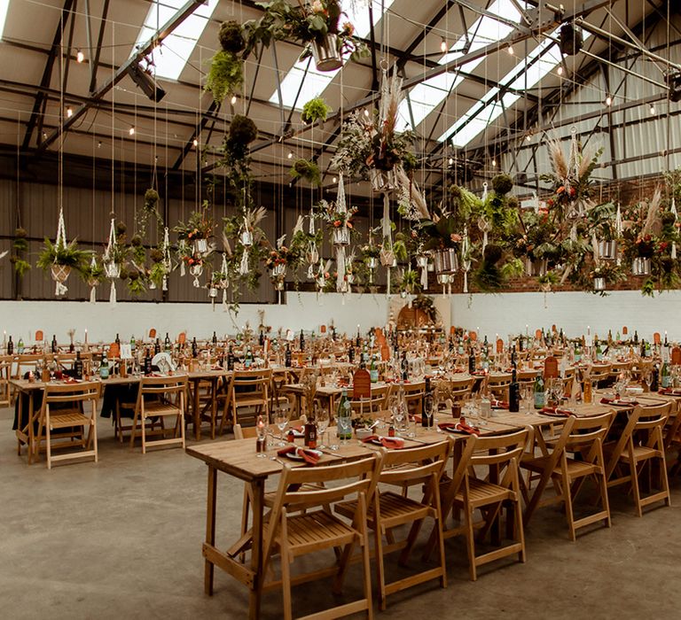 Macrame hanging plant decor for industrial warehouse wedding based in Sheffield with wooden tables and chairs