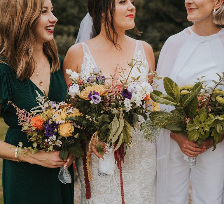 Brides with bridesmaids in green mismatched style dresses and colourful wedding bouquets 