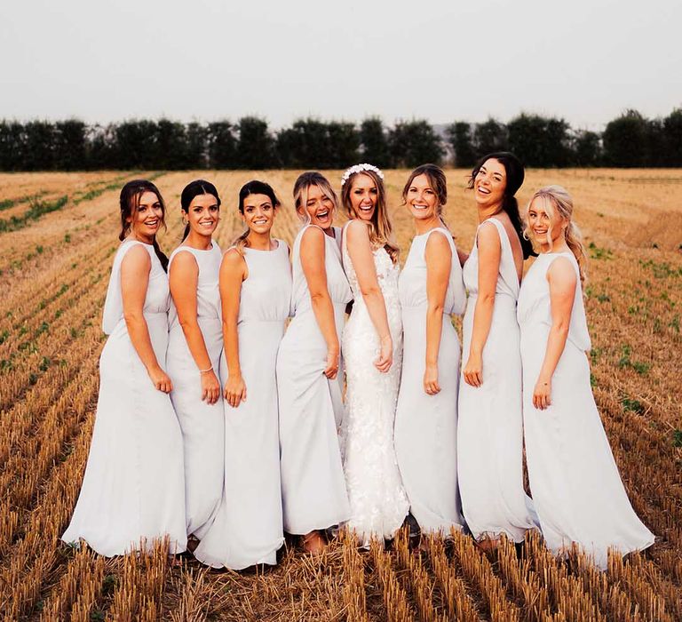 Bride in white flower headband stands with her bridesmaids in grey dresses on wedding day