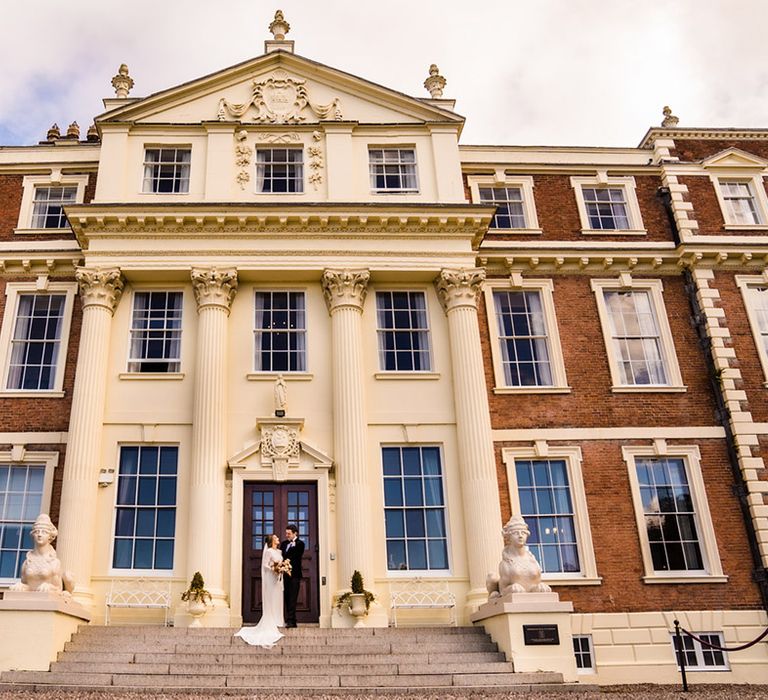 Bride and groom on the steps of their wedding venue Hawkstone Hall 