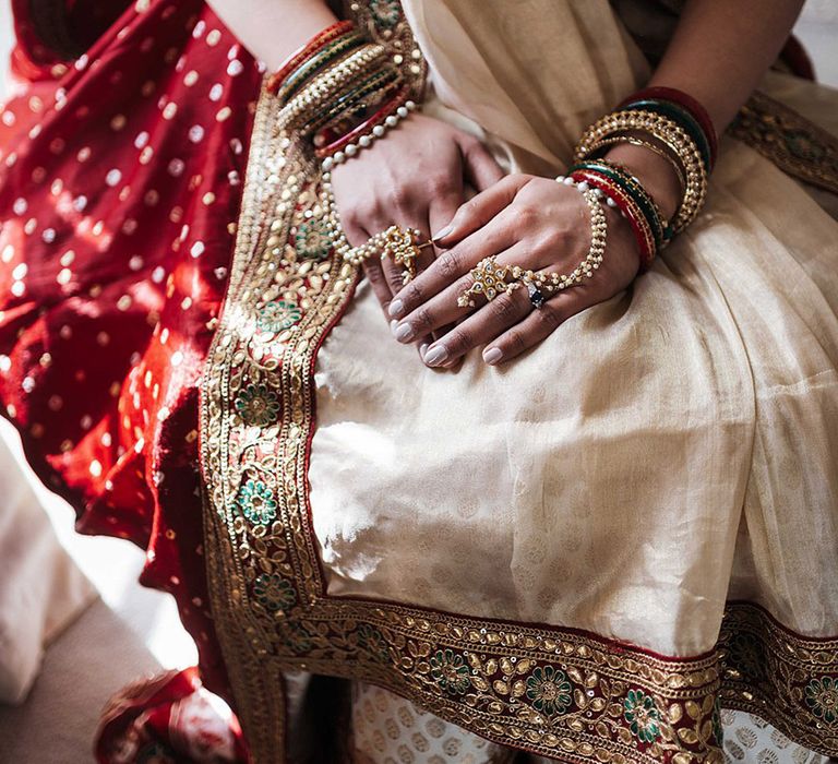 Bride wears bangles and rings in red and gold colours 