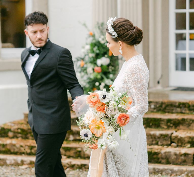 Black tie wedding at Holesfoot with bride in a beaded wedding dress with long sleeves holding a peach and white bouquet and wearing an appliqué headdress 