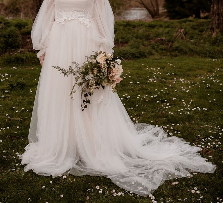 Bride in an ethereal wedding dress with tulle skirt, spaghetti straps and sheer sleeves