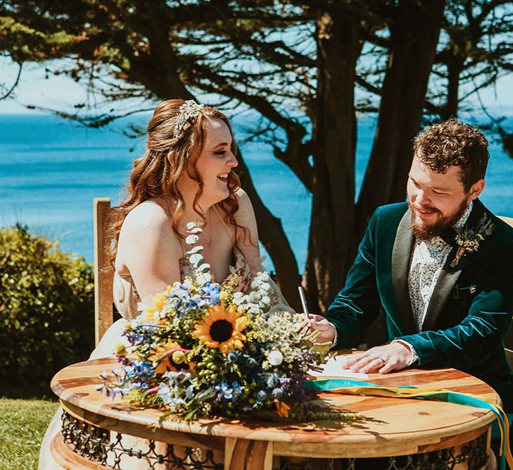 Bride & groom sign wedding certificate on sea front during Cornwall wedding 