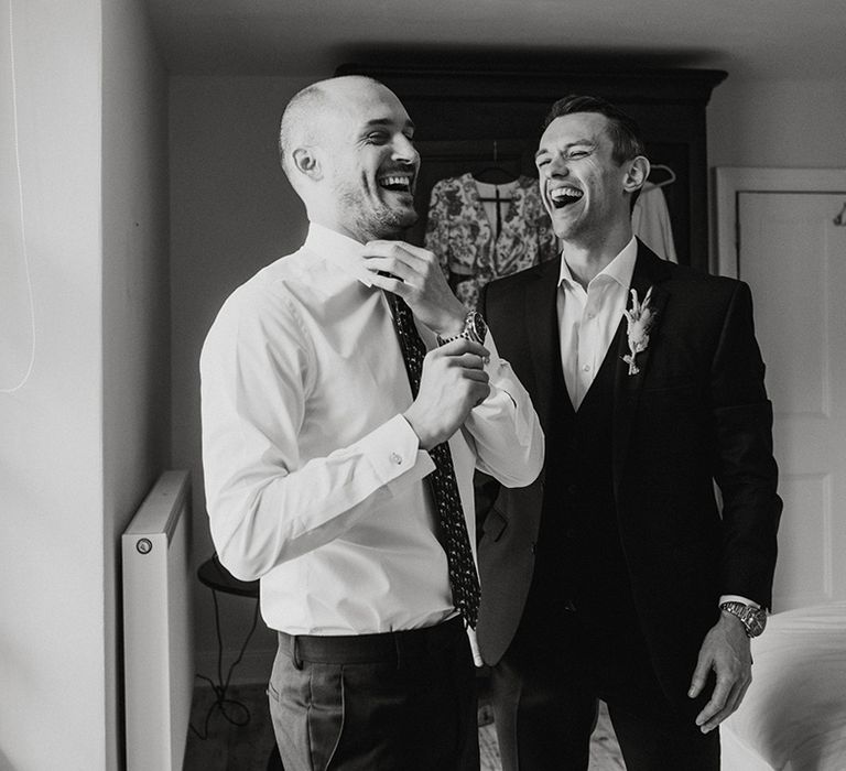 Groom laughs with groomsman as they get ready for the wedding 