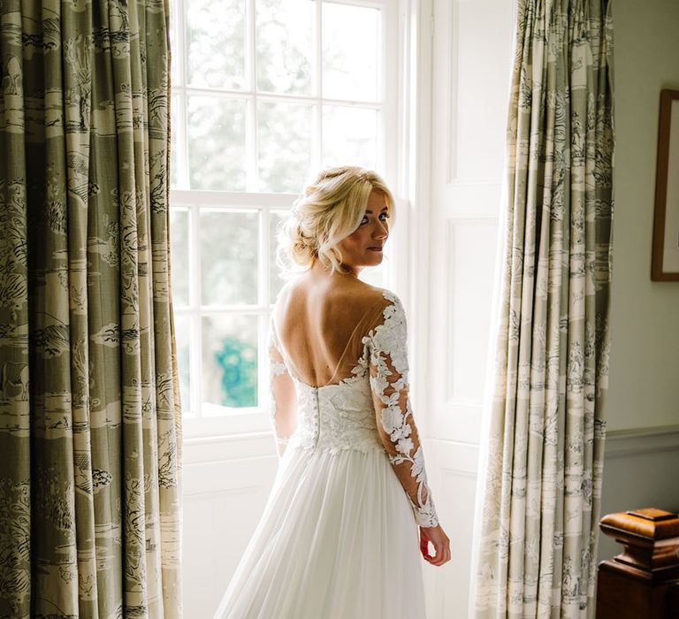 Bride wears low back Pronovias wedding dress with long sleeves and lace complete with exposed buttons to the back 