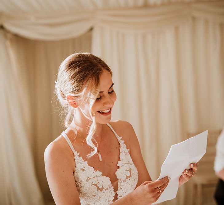 Bride wearing lace wedding dress gives speech during wedding reception in marquee 