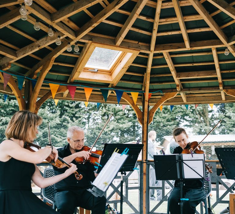 String quartet play outdoors for wedding ceremony